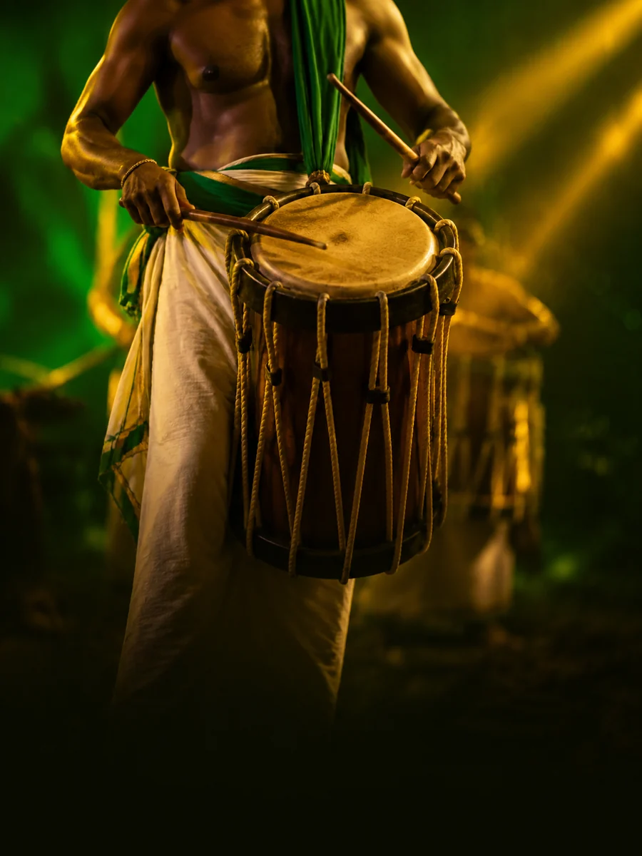 A chenda player mid-stroke, the drum slung at the waist